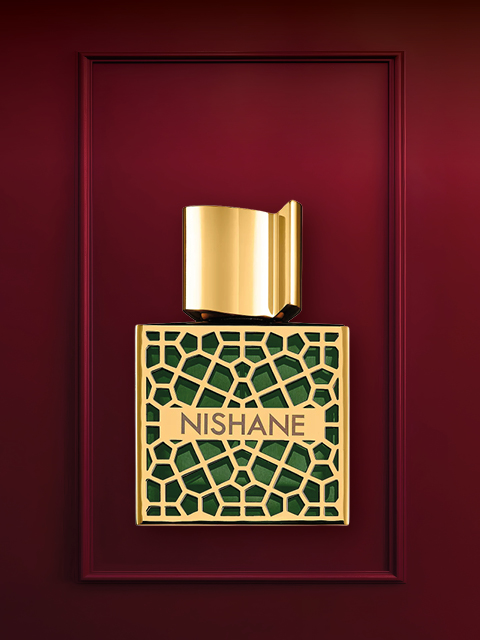 Su uno sfondo rosso intenso, si vede un flacone di profumo di lusso con un design in oro e cristalli. Sotto si trova il tappo del flacone. Sopra, in bianco, si legge la scritta "REGALI DI LUSSO".