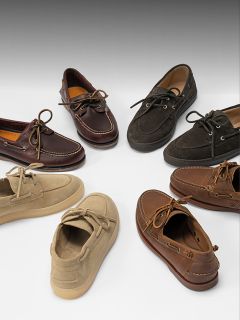 Sette paia di scarpe da barca in vari colori, tra cui marrone, marrone chiaro e nero, disposte in cerchio su uno sfondo bianco.